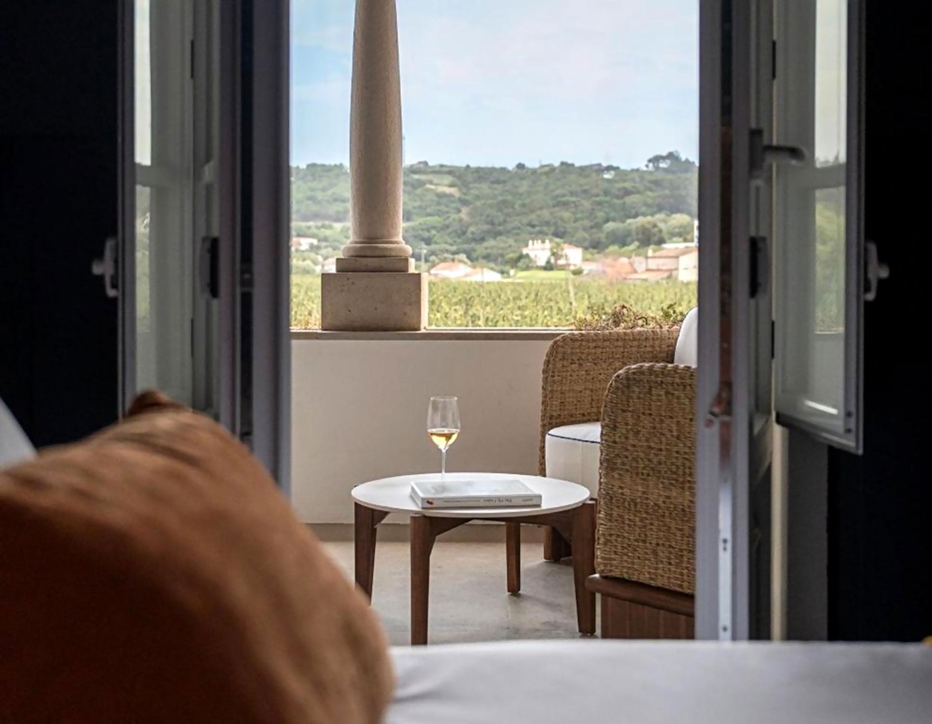 Varanda com vista para vinhas em AndTales, com mesa, cadeira e taça de vinho.
