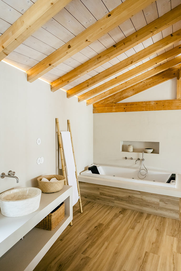 AndTales spa bathroom: wooden beams, stone sink, and soaking tub.