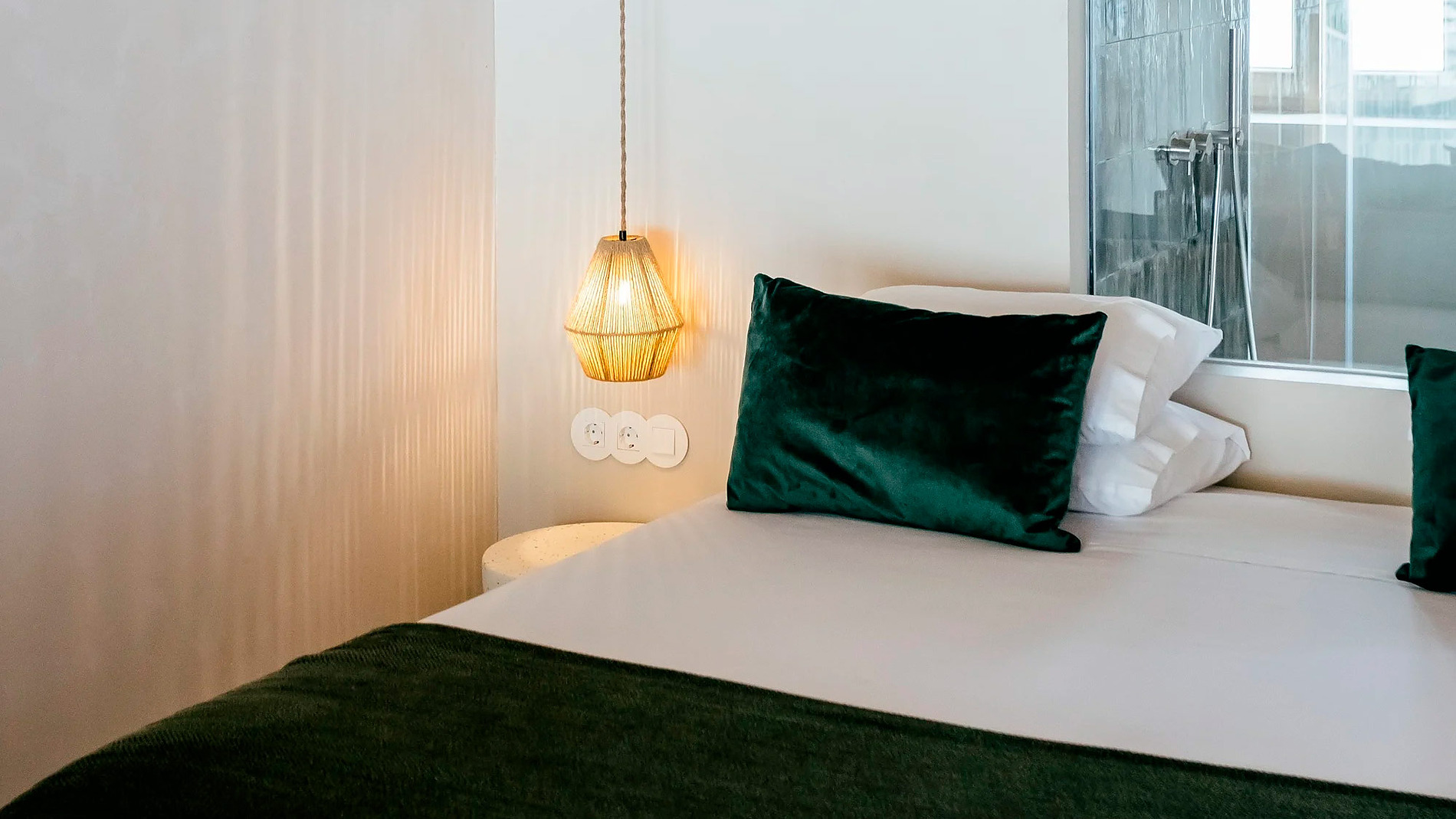 Cama aconchegante no AndTales, com travesseiros de veludo e lustre rústico.