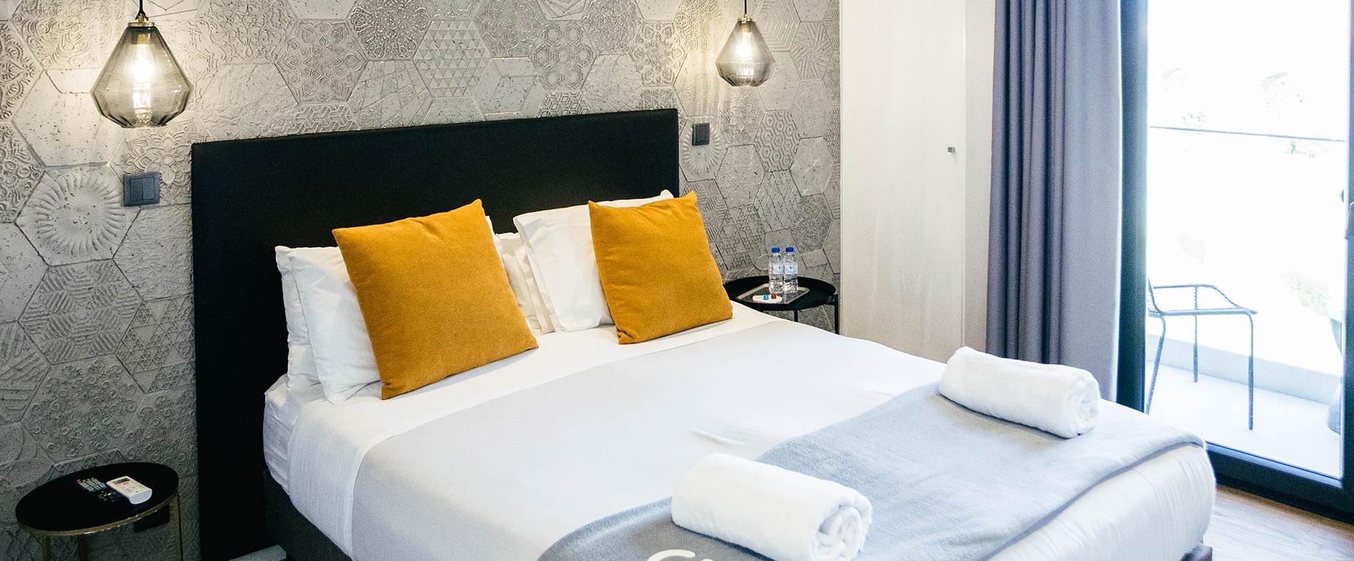 Cozy hotel room with a plush bed, navy pillows, desk, and phone. AndTales accommodation.