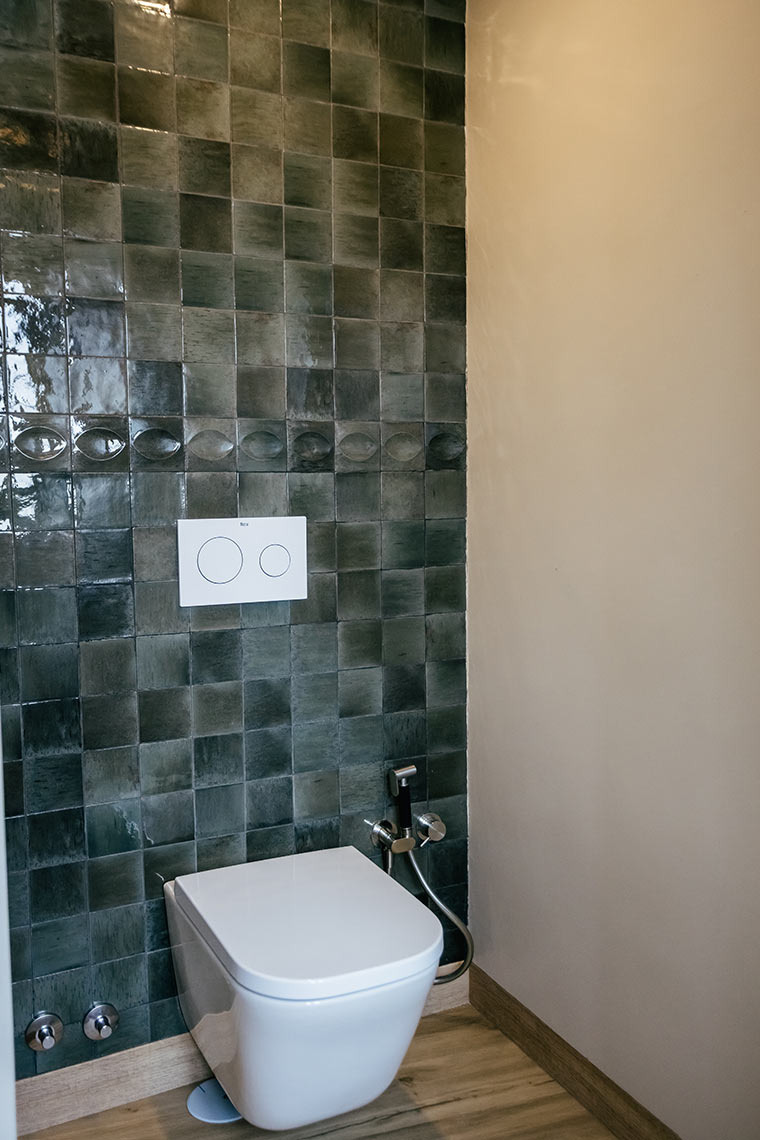 Stylish bathroom at AndTales Hotel: modern toilet, tiled walls, and bidet spray.