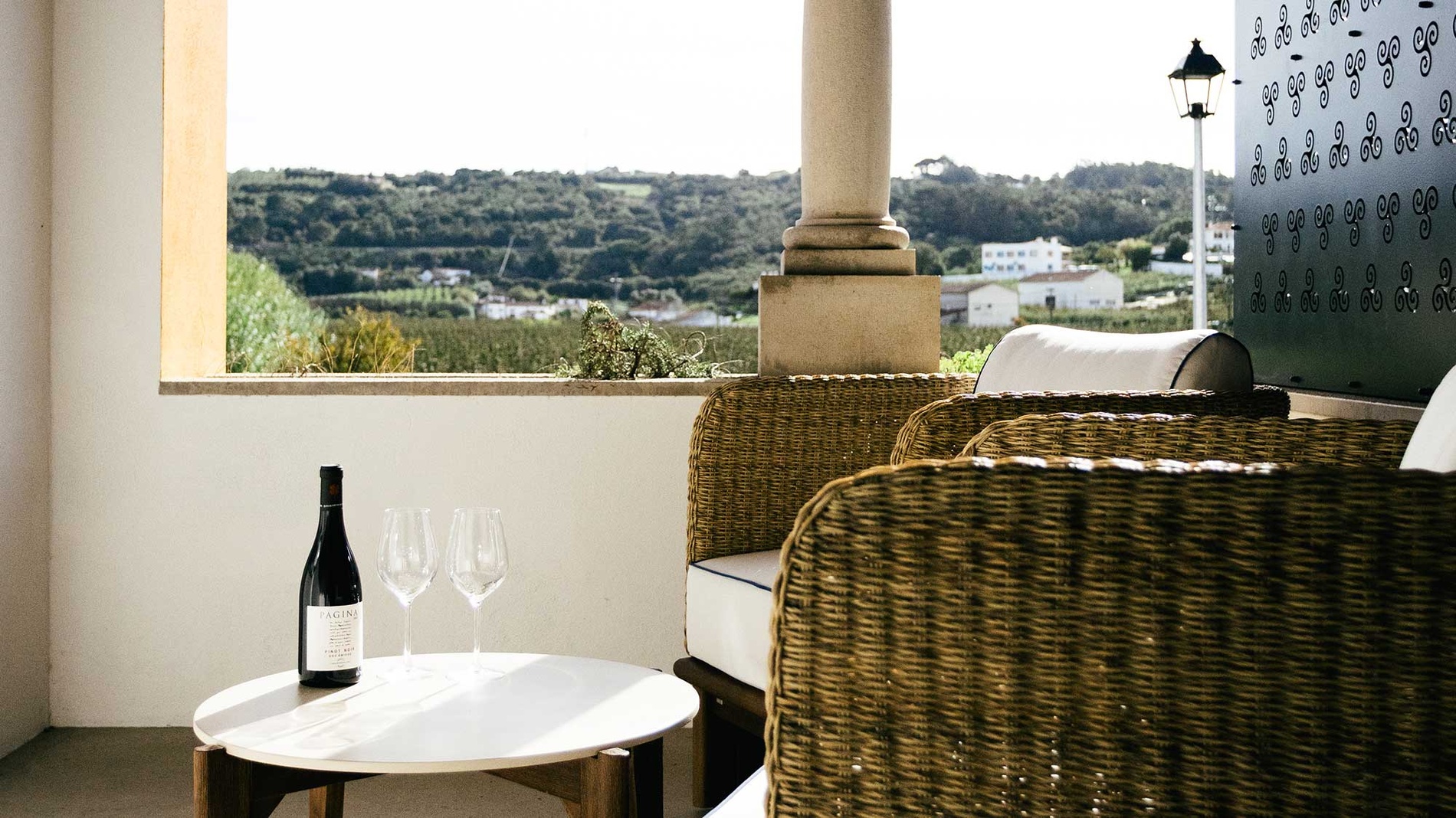 Varanda com vista e vinho em hotel AndTales, ideal para relaxar.