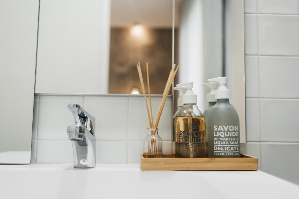 Bathroom sink with liquid soap, diffuser, and faucet. An AndTales signature clean aesthetic.