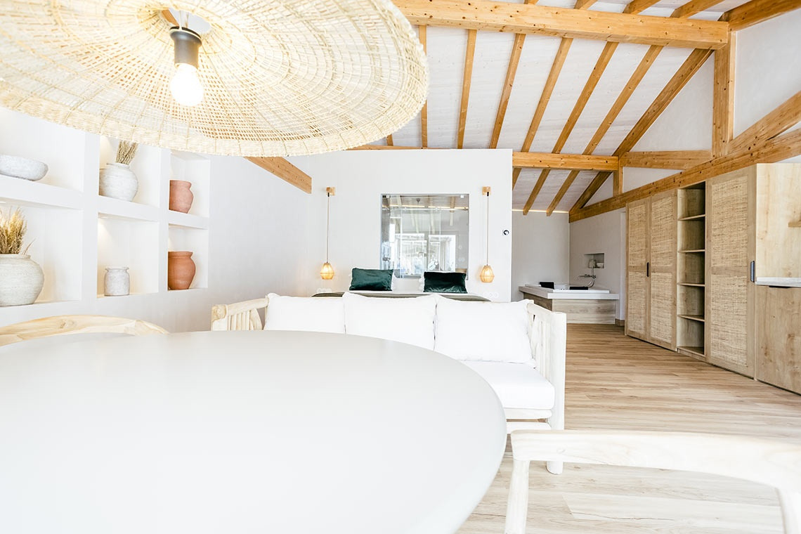 Modern bedroom at AndTales Hotel with white sofa, wooden beams, and designer light fixtures.