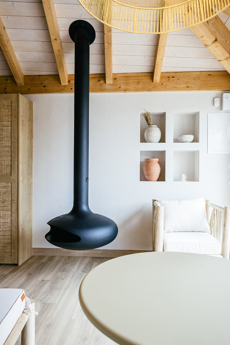 Modern black hanging fireplace in AndTales hotel's living area with rustic furniture.
