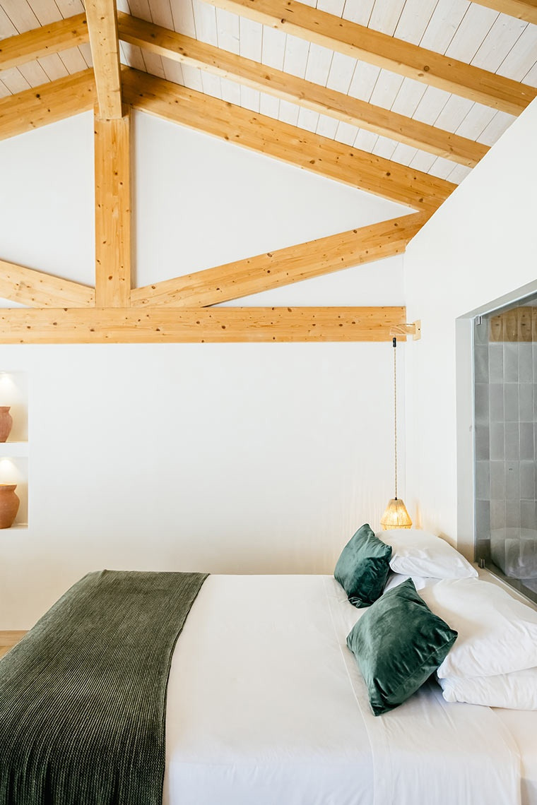 Rustic yet modern bedroom with wooden beams at AndTales hotel.