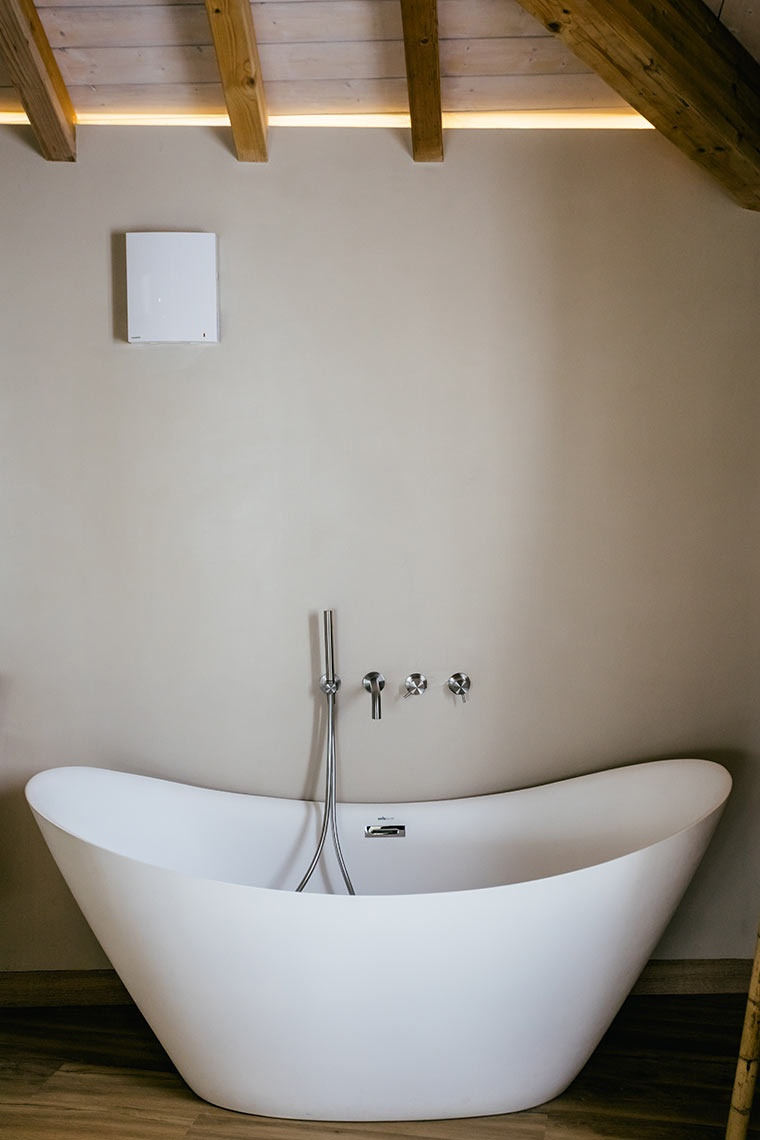 Modern freestanding bathtub and showerhead in a luxurious AndTales bathroom.