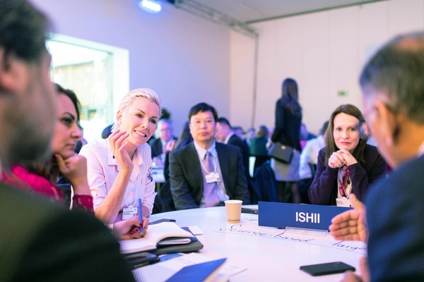 Sala de conferências com pessoas em reunião, apresentando o nome "ISHII" e o tema "Science-based".