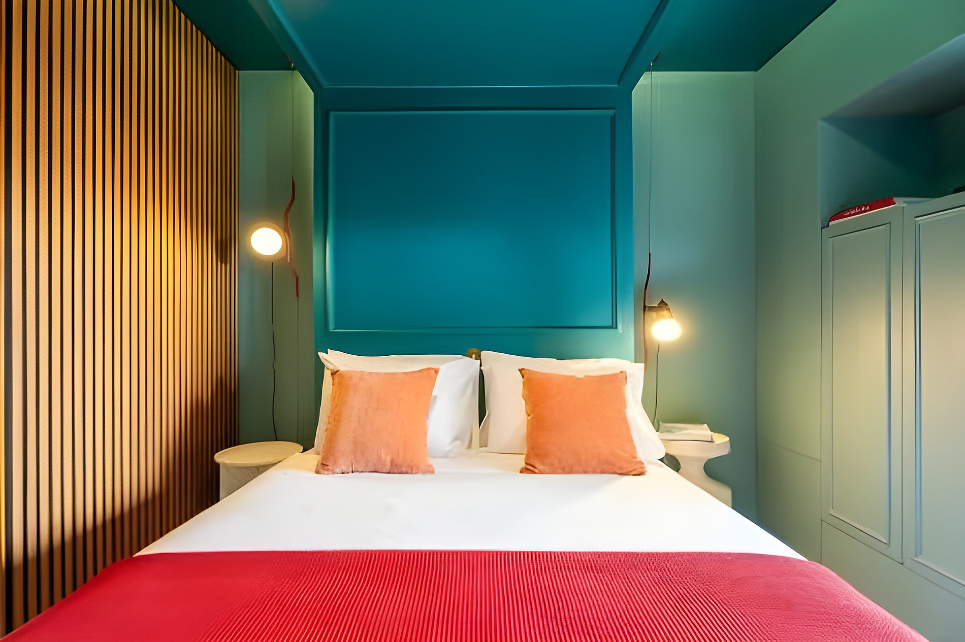Quarto AndTales com cama, almofadas laranjas e decoração moderna.