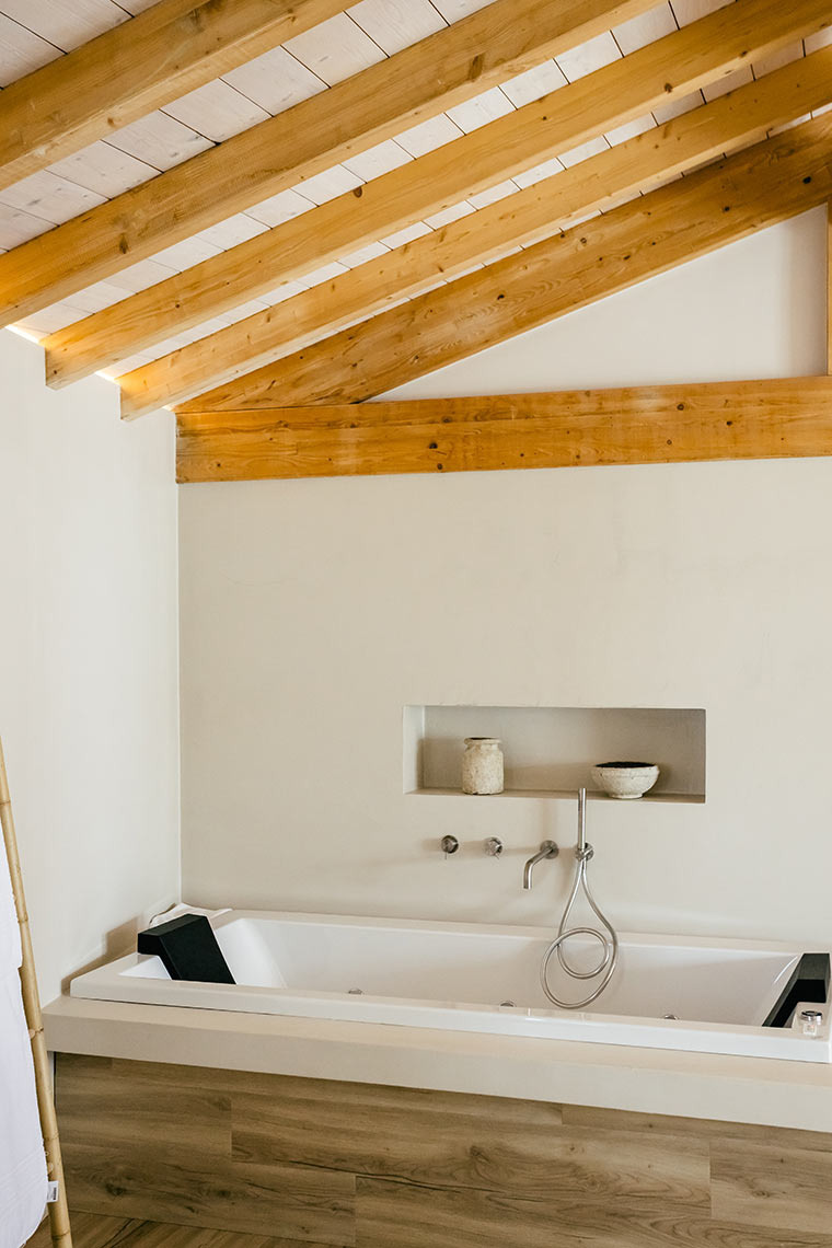 Luxury AndTales bathroom: bathtub with wooden beams and minimalist decor.