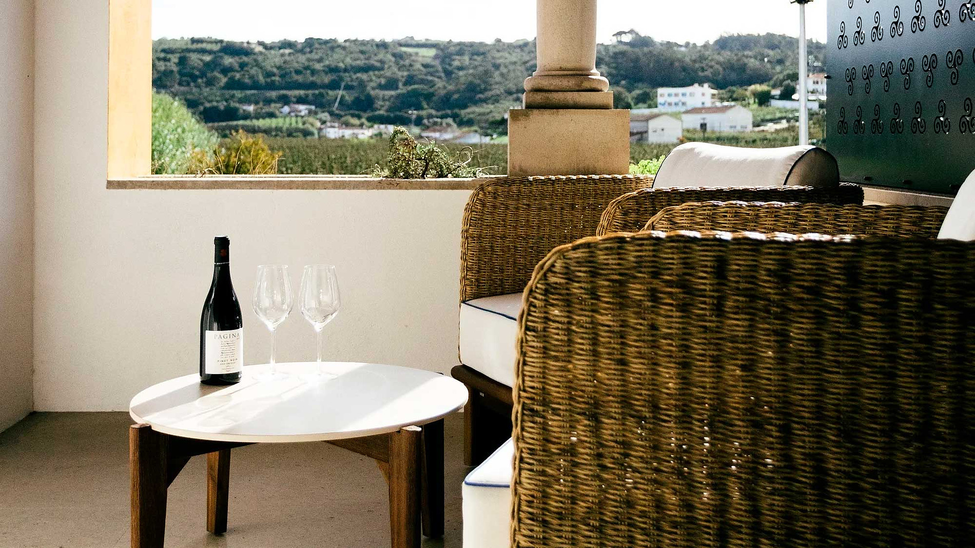 Uma garrafa de vinho e taças em uma mesa, com vista AndTales.