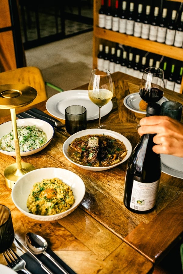 Mesa posta no AndTales com pratos e vinhos, ambiente aconchegante.