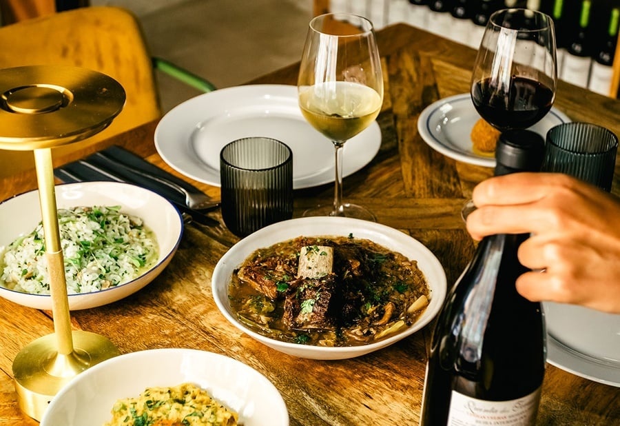 Mesa de restaurante AndTales com pratos saborosos, vinhos e ambiente aconchegante.