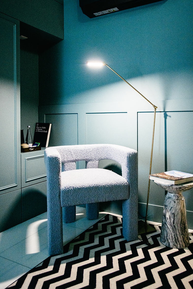 Poltrona AndTales e mesa lateral em mármore em quarto azul-petróleo com tapete zigzag.