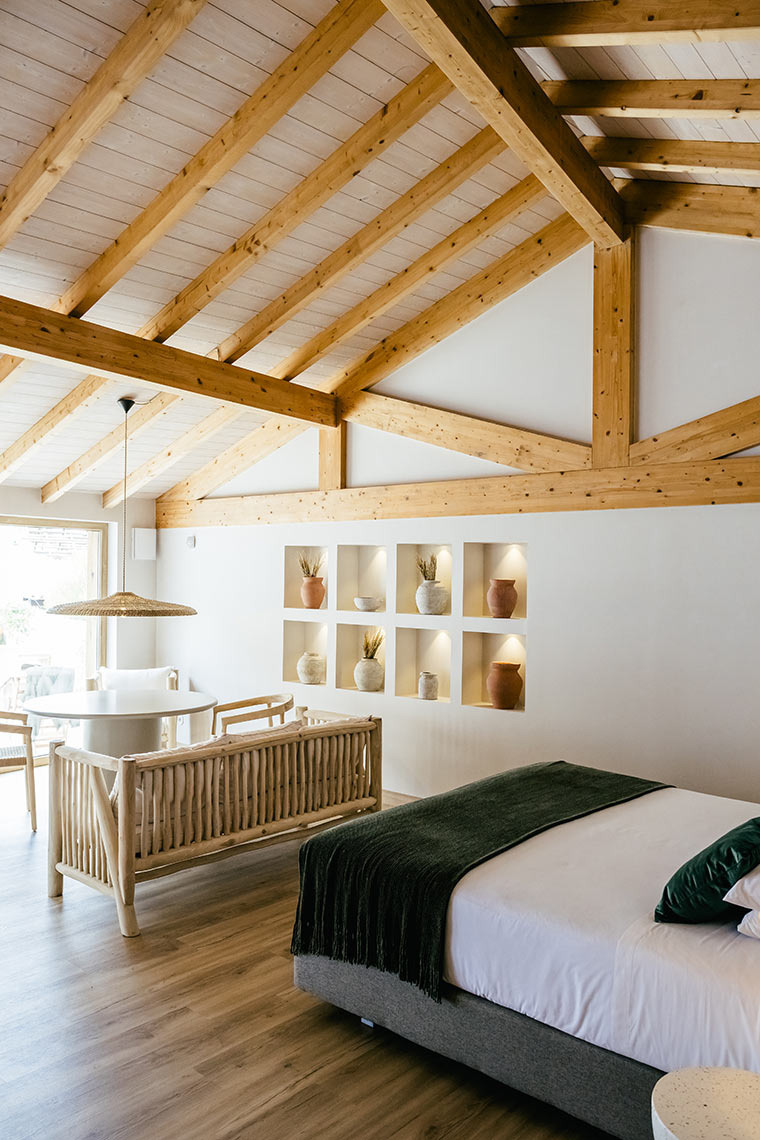 Cozy AndTales hotel room with vaulted wood ceiling, natural wood furniture, and a plush bed.