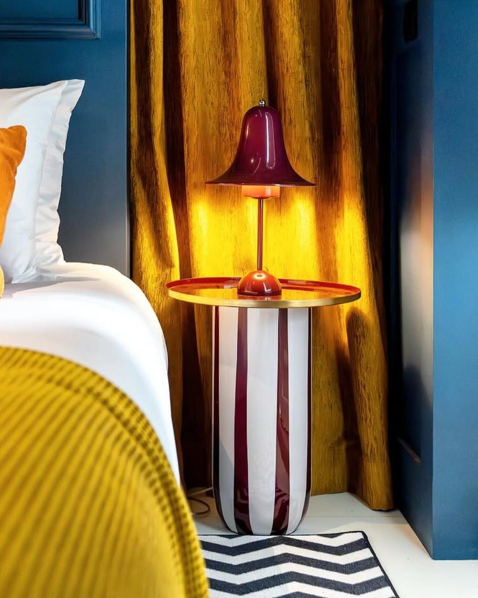 AndTales: Mesa lateral moderna em quarto de hotel com luminária de mesa escura.