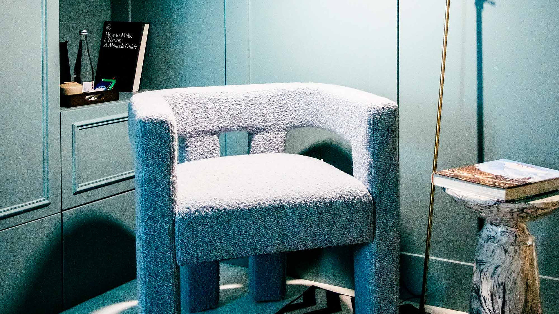 Poltrona AndTales e mesa lateral em mármore em quarto azul-petróleo com tapete zigzag.