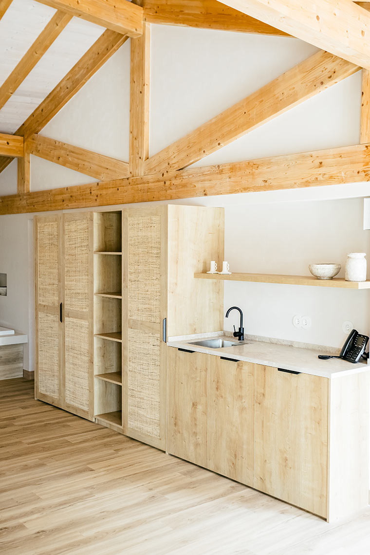 Modern kitchen area with light wood cabinets and exposed beams at an AndTales property.