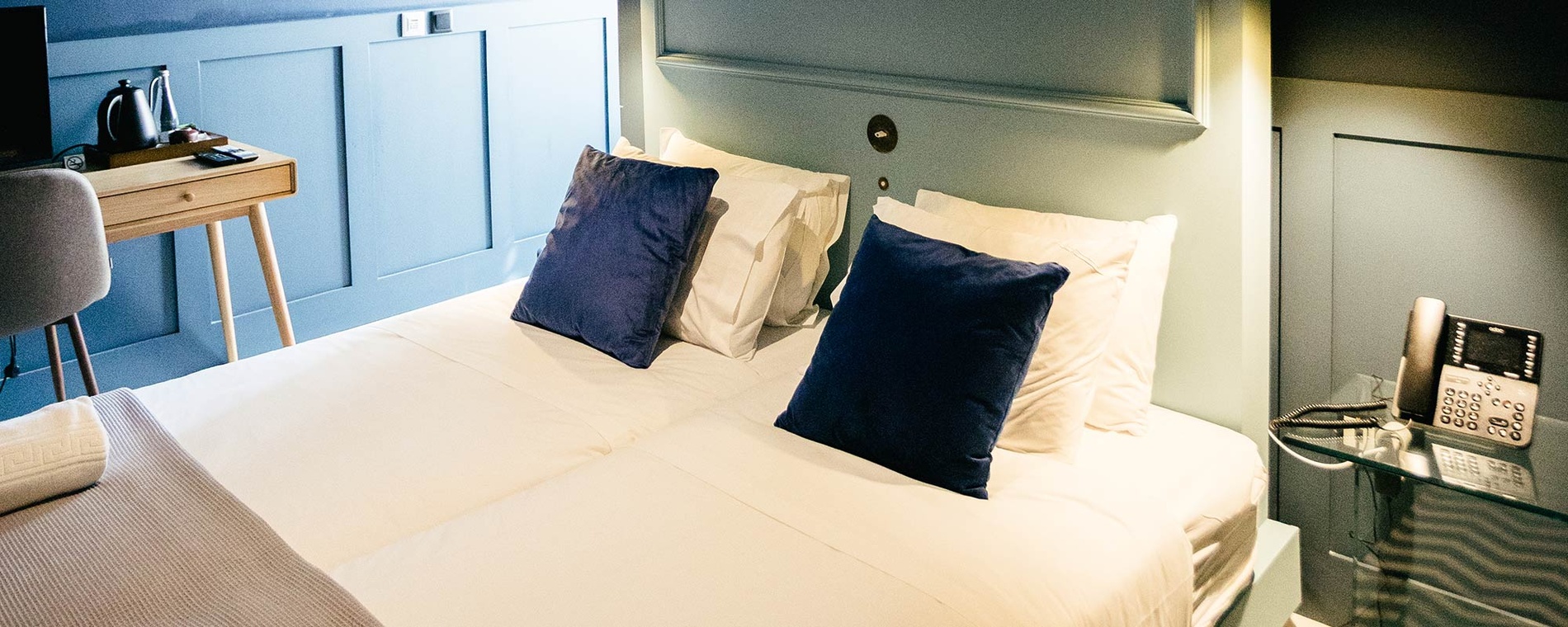 Quarto confortável em hotel AndTales com cama dupla, travesseiros e telefone.