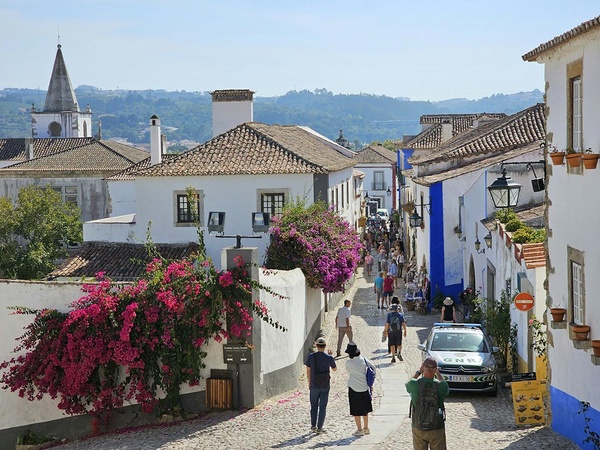 Rua pitoresca com flor de buganvílias em Óbidos, um cenário AndTales.