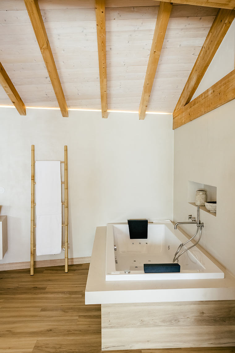 Luxurious AndTales bathroom with jacuzzi, bamboo towel rack, and modern wood accents.