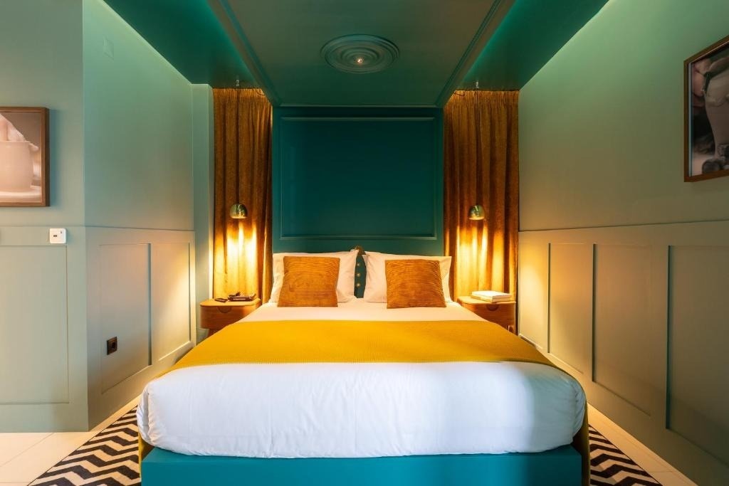 Quarto de hotel AndTales com cama confortável, almofadas e manta vibrante.