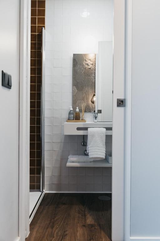 Modern AndTales hotel bathroom with white tiles, wooden floor, and a sleek vanity.