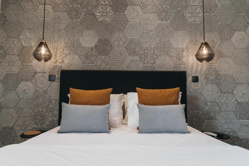 Cozy bed with black headboard and AndTales pillows, facing textured wall.