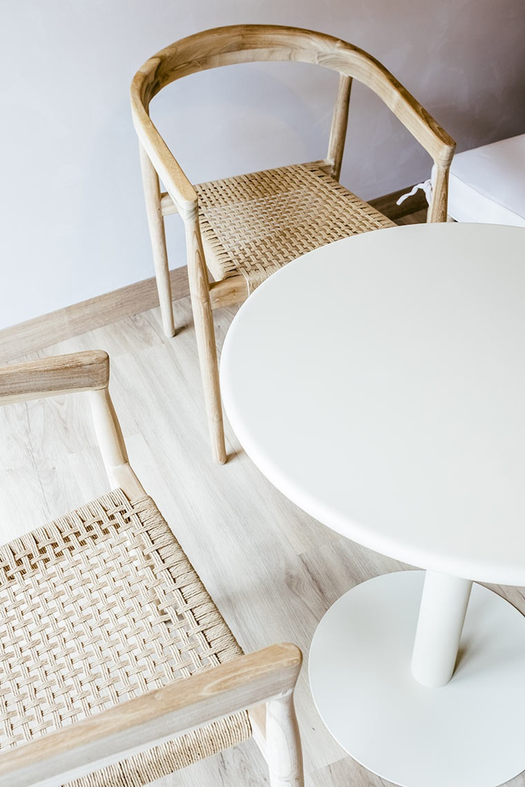 AndTales hotel: Two minimalist wood chairs with woven seats at a round white table.