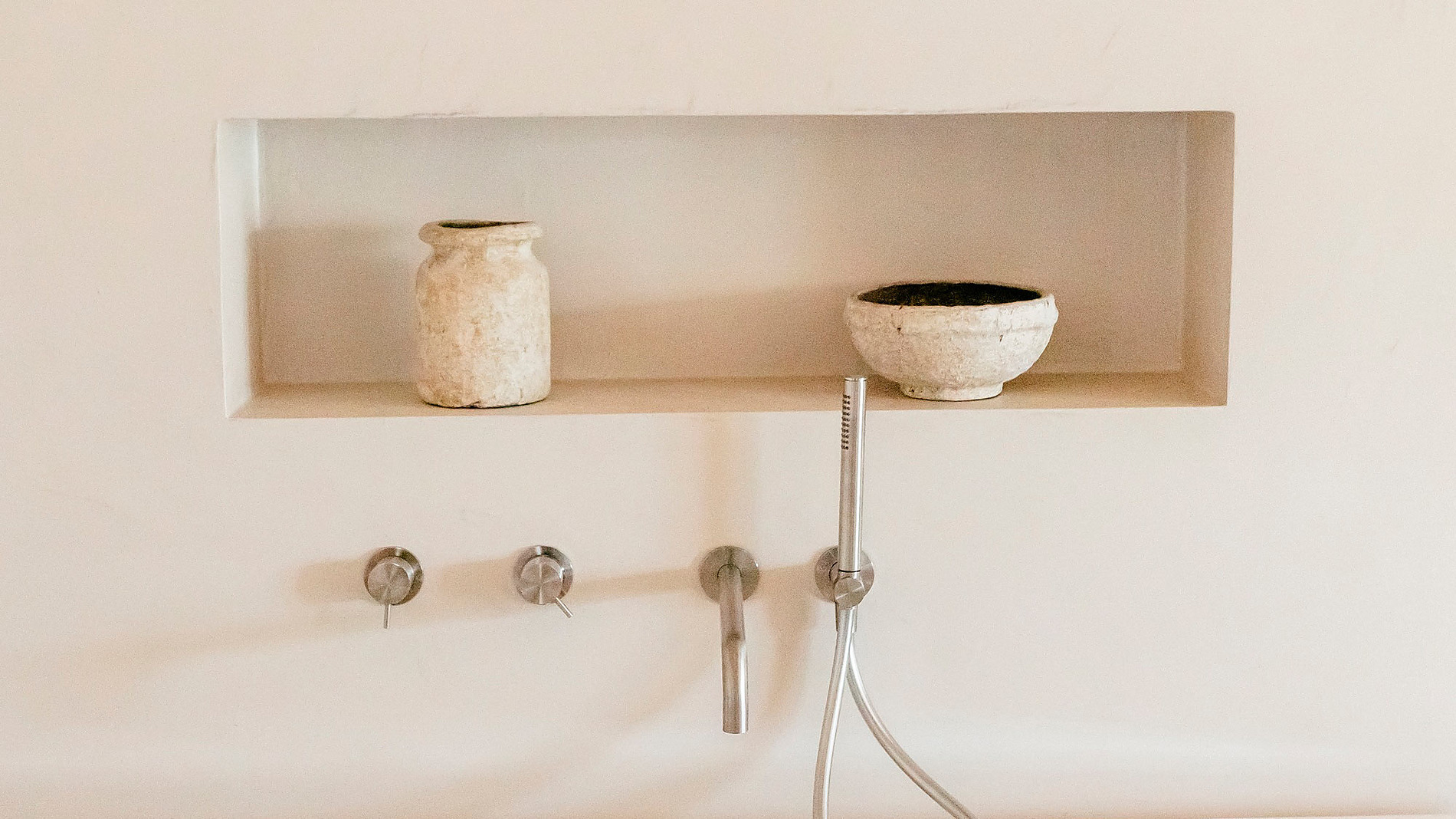 Banheira luxuosa em AndTales com ducha e nicho decorativo, um convite ao relaxamento.