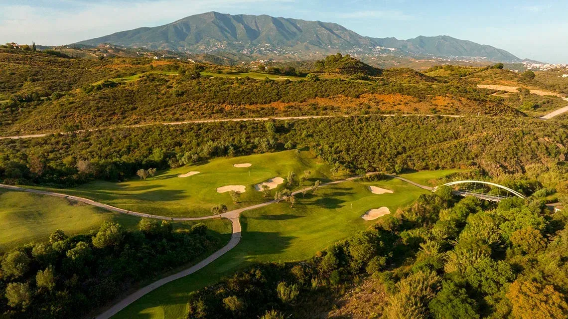 Golf course at Angela's hotel with mountains and a bridge.