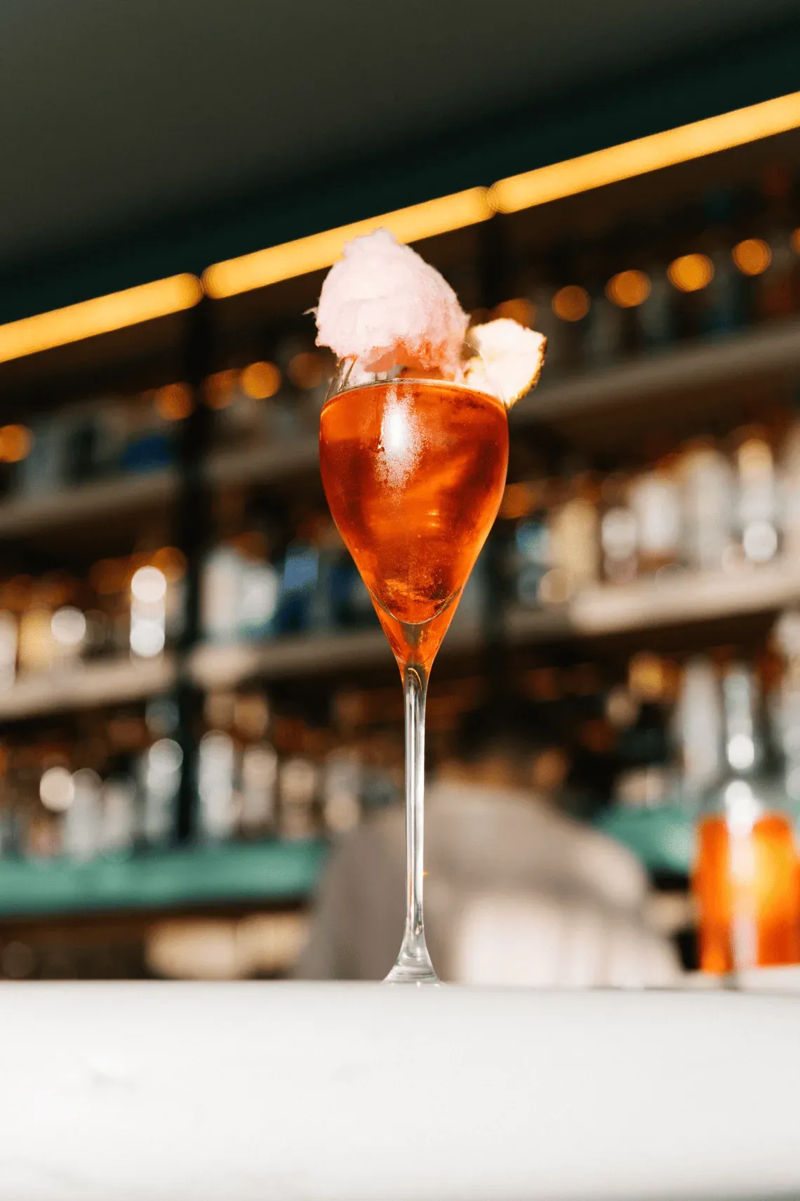 Cóctel rosado de Ángel con algodón de azúcar en bar de hotel.