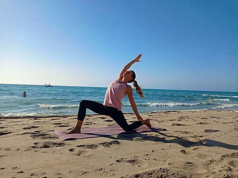 Angela pratique le yoga sur la plage, une vue sereine.