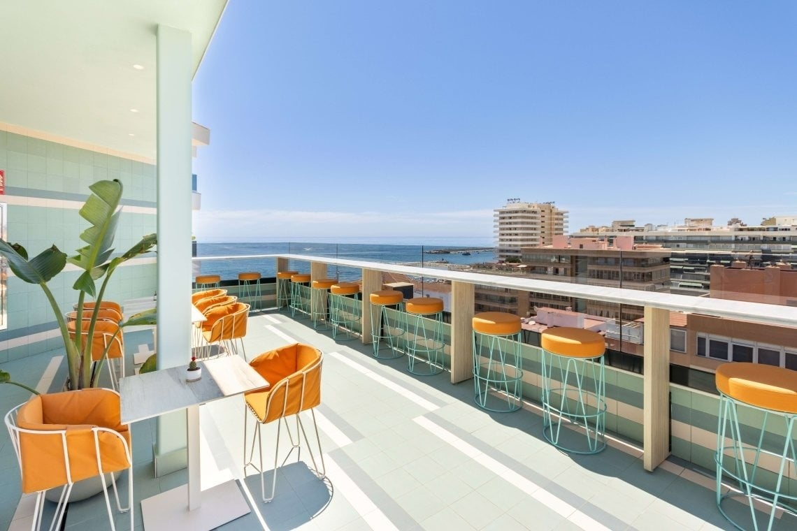 a balcony with tables and chairs overlooking the ocean