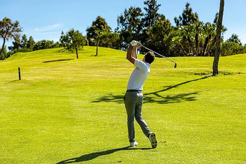 Golfista profesional Angela en pleno swing, practicando en un campo de golf de lujo.