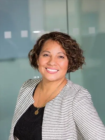 Angela, profesional sonriente con blazer rayado en hotel.