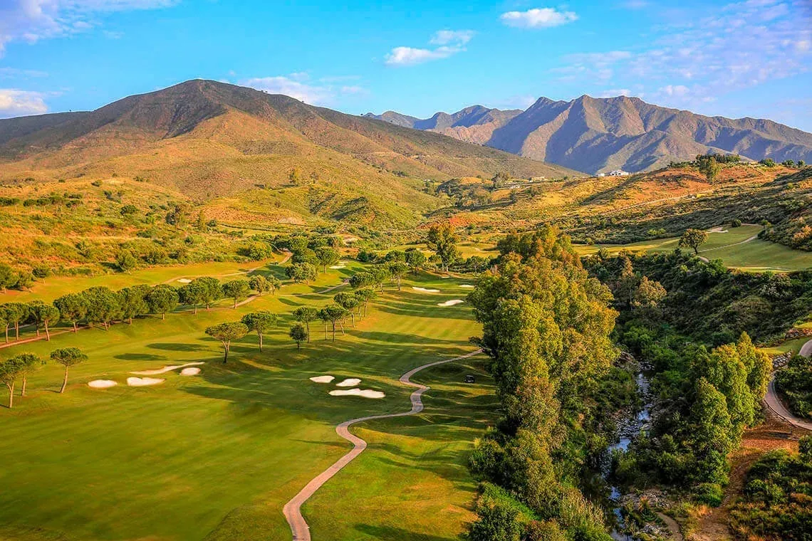 Parcours de golf Angela avec montagnes et rivière, idéal pour des vacances golfiques.