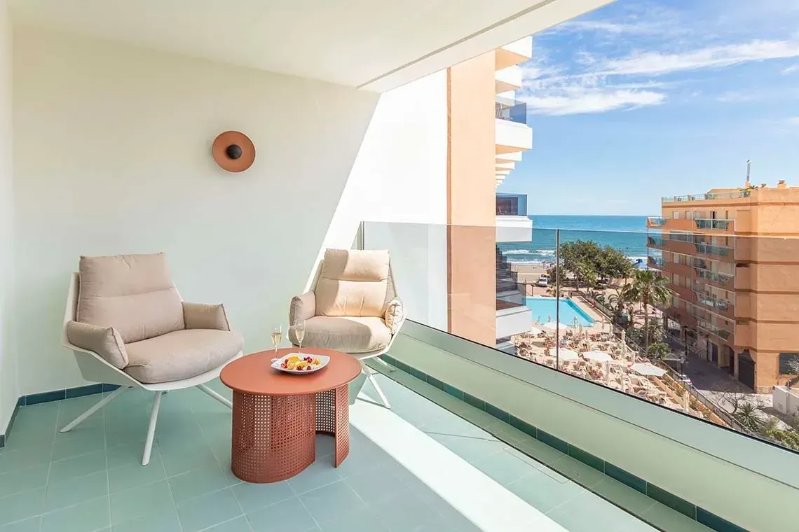 Balcón moderno con sillas, mesa y vista al mar, perfecto para unas vacaciones Angela.
