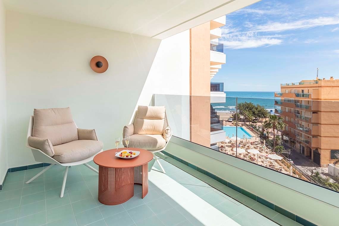 dos sillas y una mesa en un balcón con vista al océano