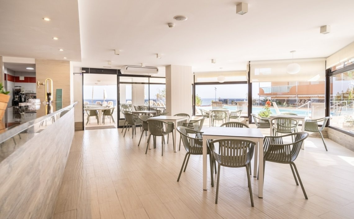 a restaurant with tables and chairs and a pool in the background