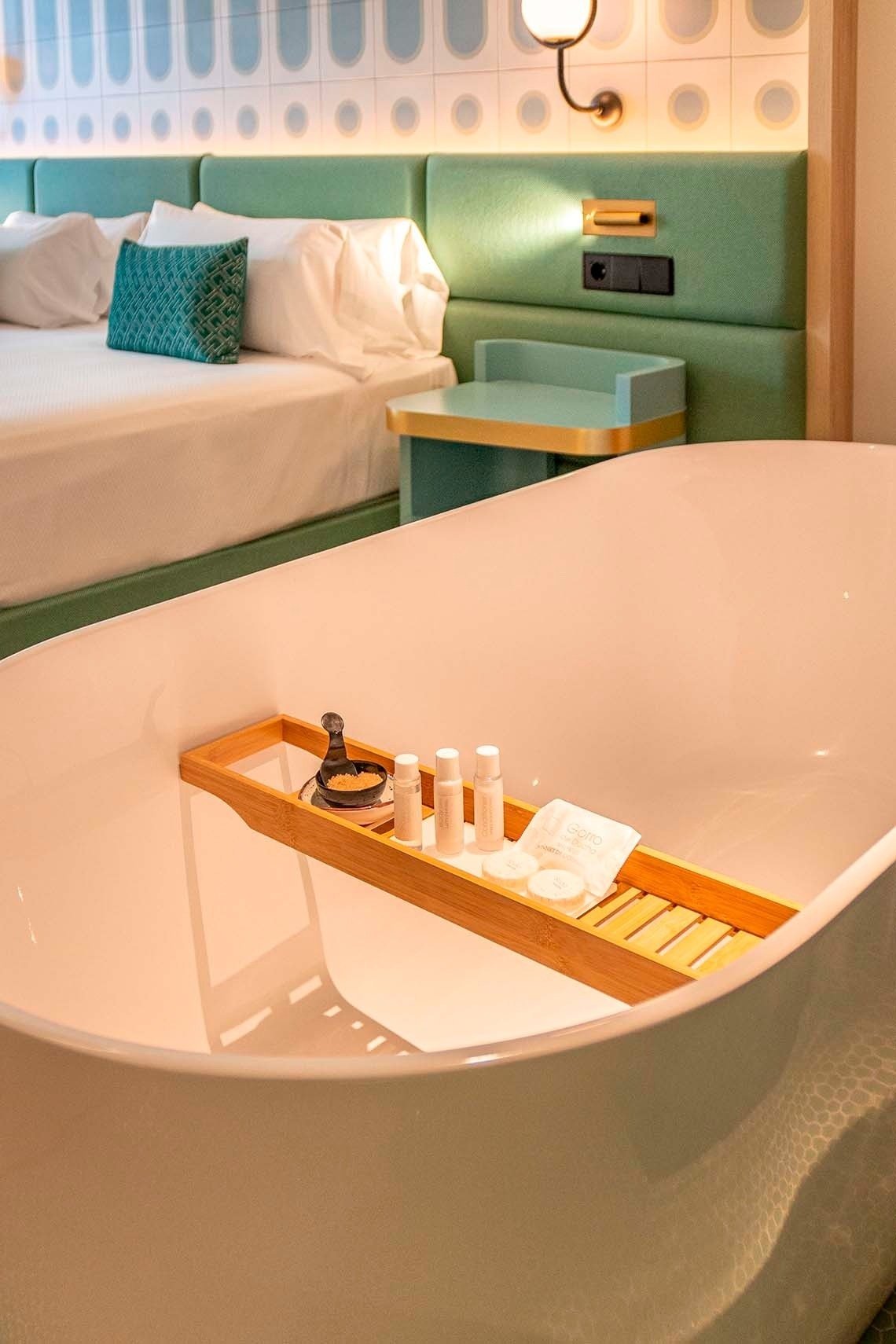 a bathtub with bottles on a wooden tray in a hotel room