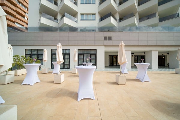 Terraza con mesas altas y sombrillas, perfecta para eventos al aire libre Angela