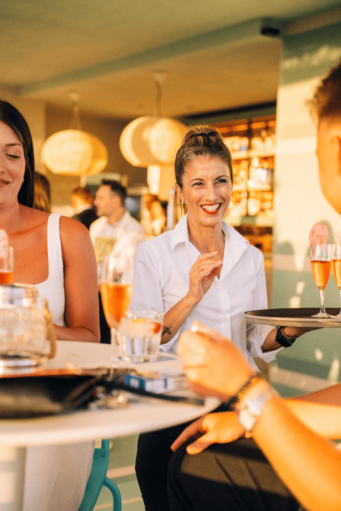 une femme sourit tout en tenant un plateau avec des verres de champagne