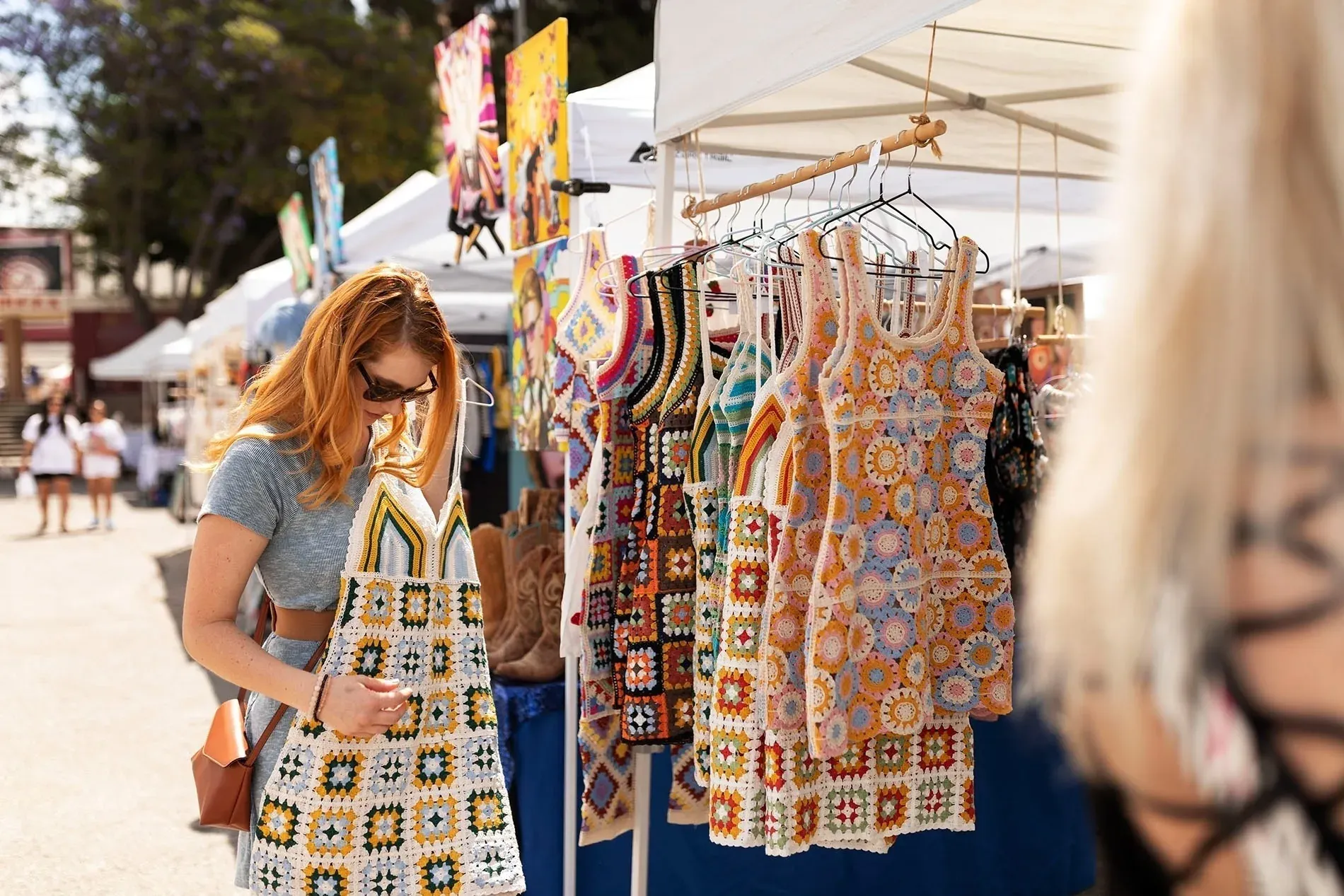 Une femme examine une robe crochetée au marché de Fuengirola, près de l'Hôtel Angela.