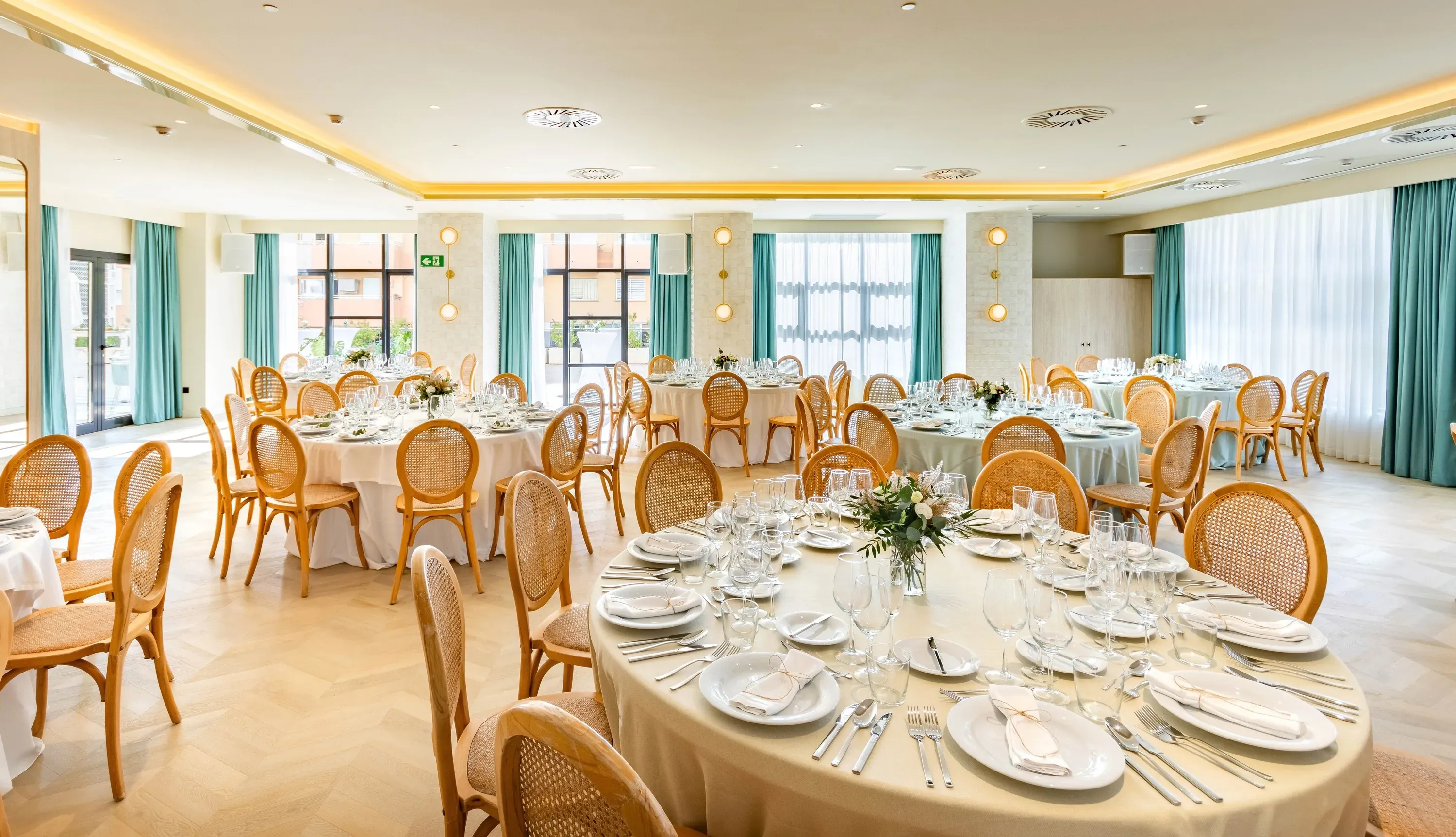 Élégante salle de réception "Angela" prête pour les banquets avec tables dressées et chaises en bois.