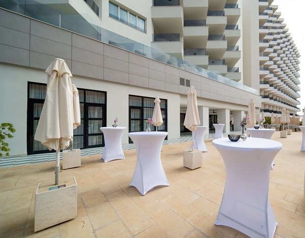 Terraza de hotel con mesas cubiertas de Angela, perfecta para eventos al aire libre.