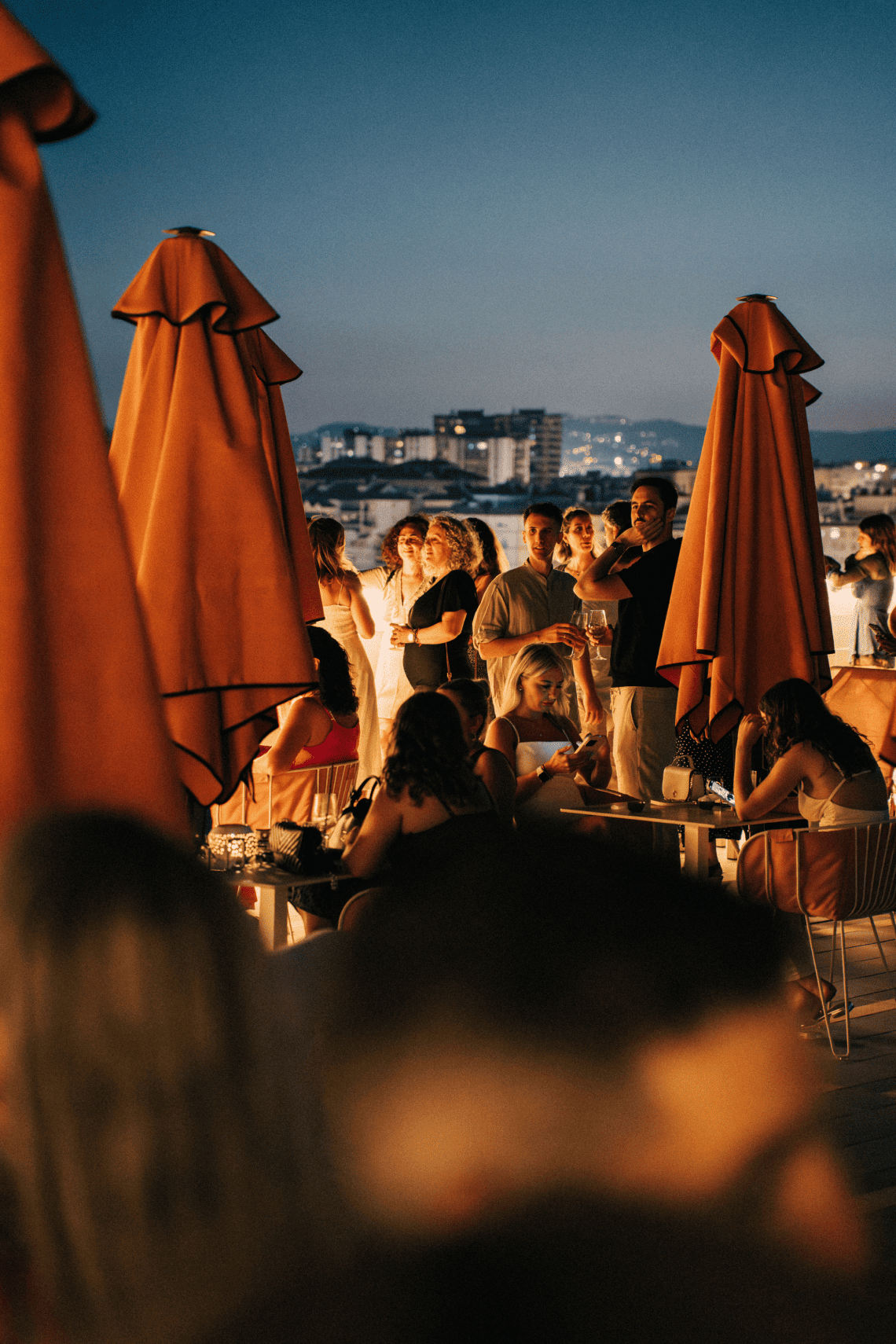 un groupe de personnes assises à des tables sous des parasols orange