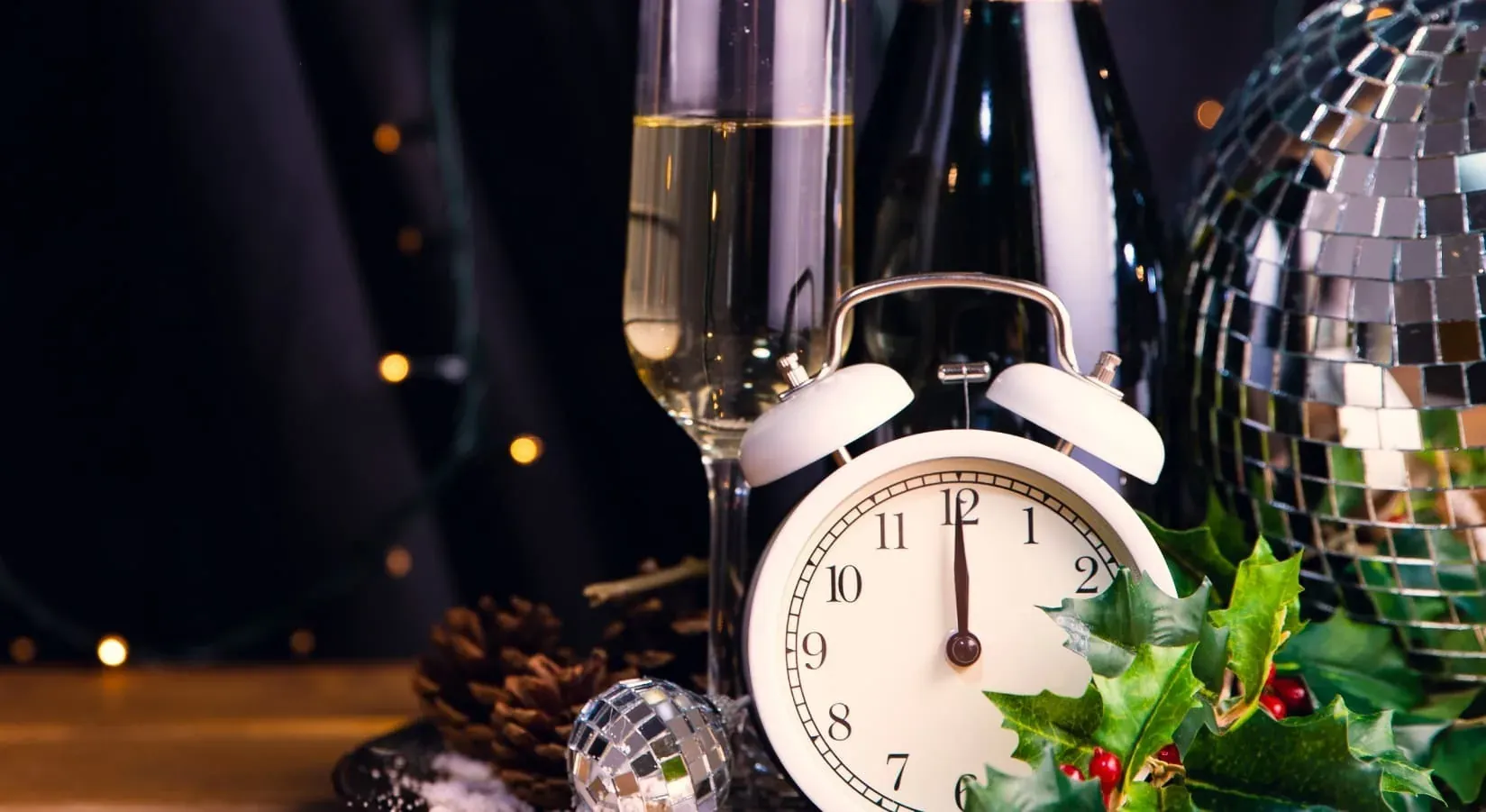Alarm clock striking midnight, champagne, and festive decor - Angela's perfect New Year's Eve.