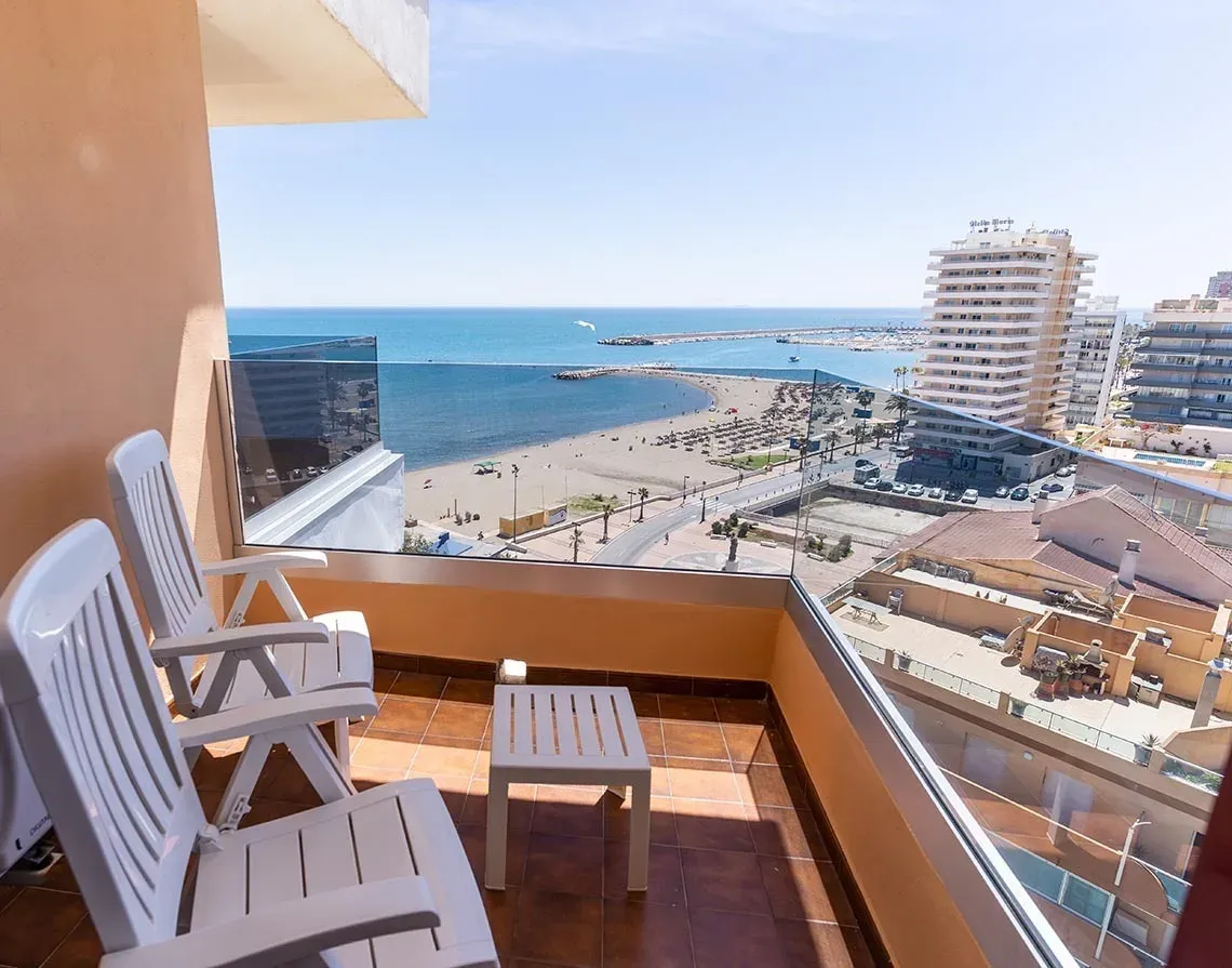 Balcón del Hotel Angela con vista al mar y sillas blancas.