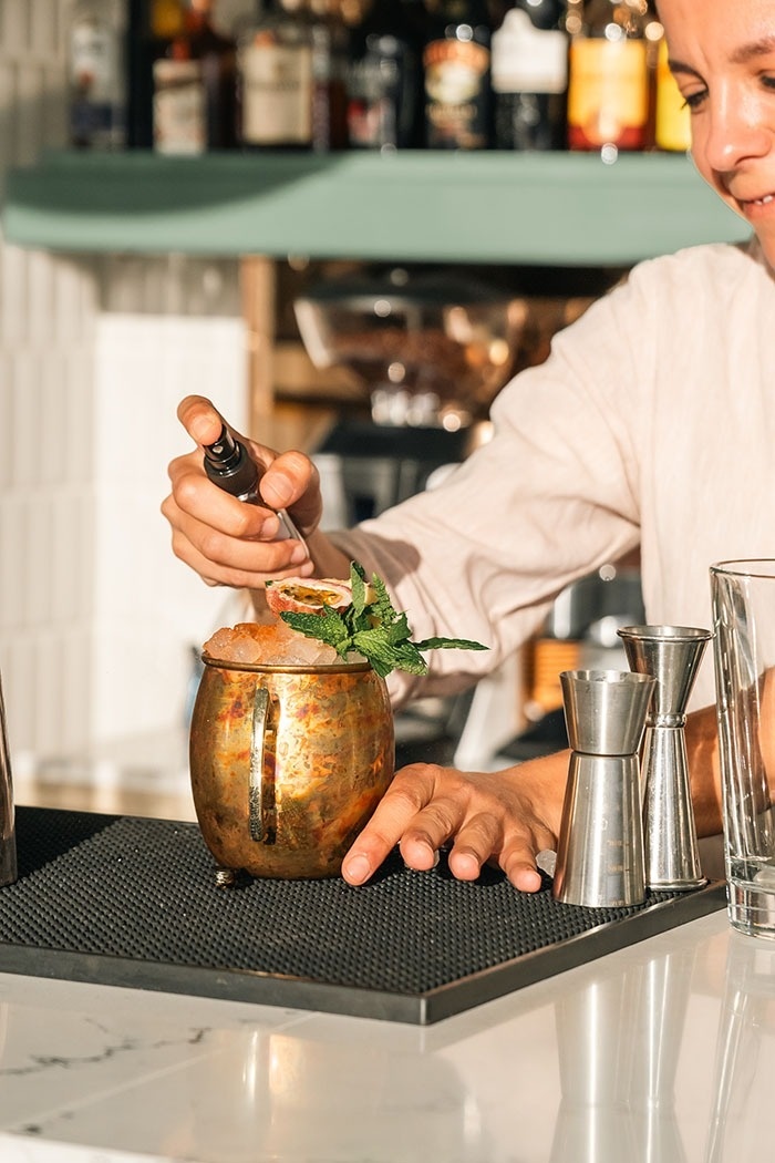 un barman prepara un cóctel en una taza de cobre